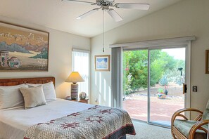 A bedroom with a bed, a ceiling fan, a painting, a lamp, and a view through a glass door. - Bright home in Sun City with large patio & on-site golf & swimming! (Oro Valley)