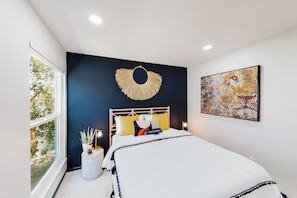 A bedroom with a bed, a window, a wall-mounted artwork, and a decorative wall piece. - Dog-friendly home near Joshua Tree NP with Cowboy pool, mountain view, firepit (Joshua Tree)