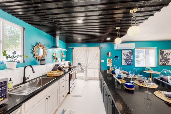 Une cuisine moderne avec un plafond noir, des murs de couleur turquoise et un îlot central aménagé en coin repas.