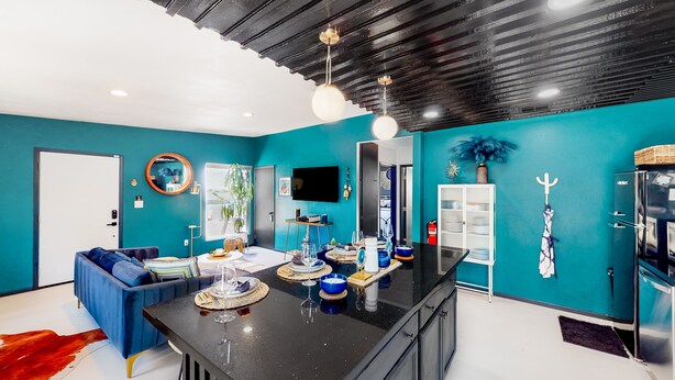 Eine moderne Küche mit schwarzem Arbeitsplatz, türkisfarbenen Wänden und einem blauen Sofa.