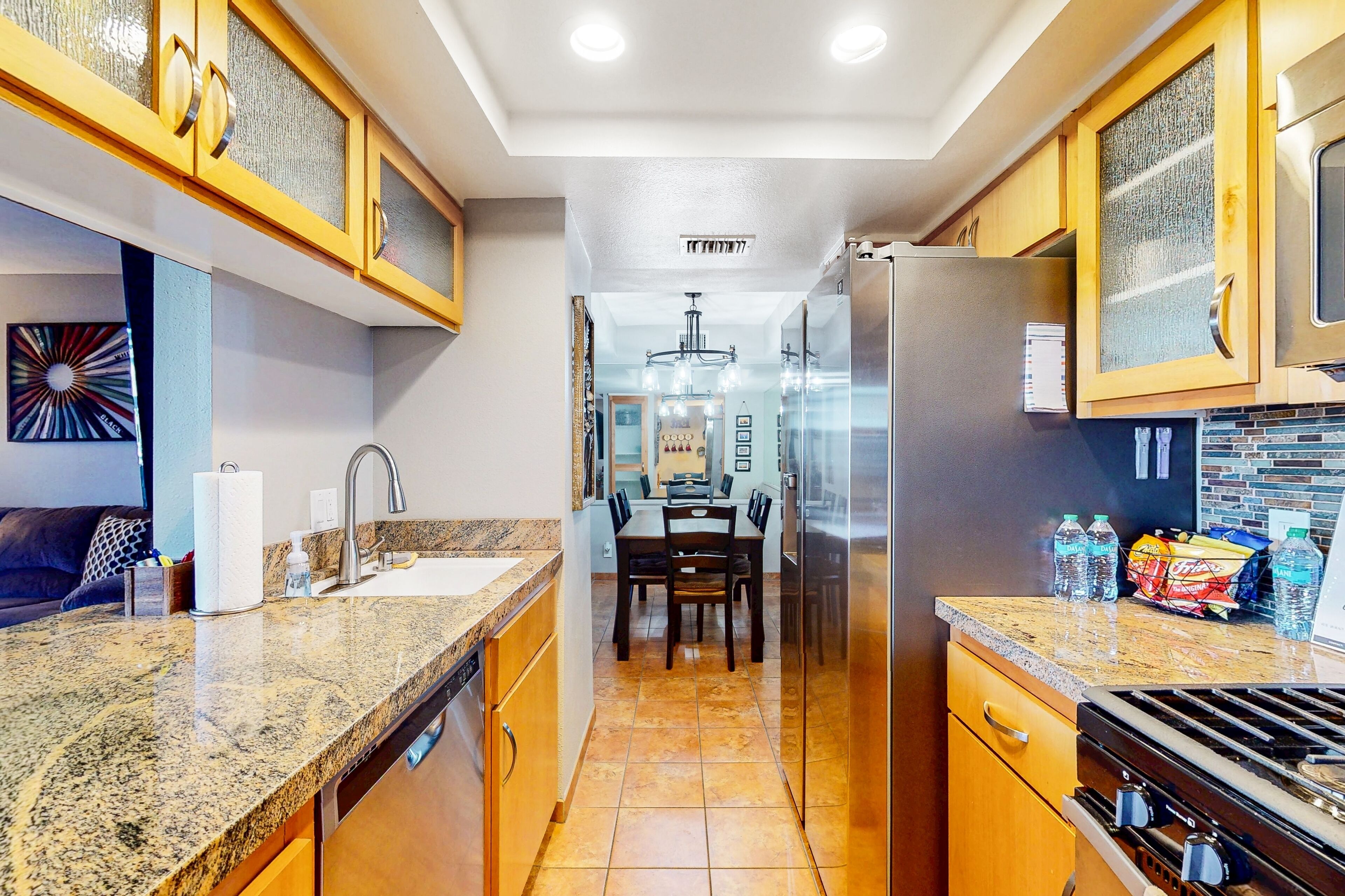 A modern kitchen with granite countertops, stainless steel appliances, and wooden cabinetry.
