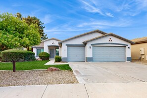 A two-story house with a garage, a well-maintained lawn, and a large tree. - Inviting home with patio, enclosed yard, fireplace, office, streaming, W/D, AC (Goodyear)