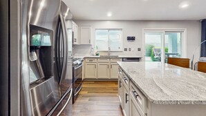 A modern kitchen with stainless steel appliances, light-colored cabinets, and a granite countertop. - Inviting home with patio, enclosed yard, fireplace, office, streaming, W/D, AC (Goodyear)