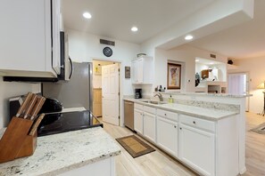 Eine moderne Küche mit weißen Schränken, einer Granit-Arbeitsplatte und einem eingebauten Backofen.