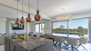 A modern kitchen with a large island, pendant lighting, and a view of the outdoors. - Stunning home in Galilzana (Galilzana)