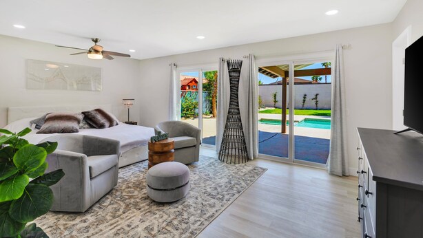 Une chambre à coucher moderne avec un lit, un canapé, un pouf et un meuble pour la télévision.