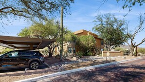 A modern house with a car parked in front, surrounded by trees and a clear sky. - Comfortable, Single-Level Condo with Free WiFi, Washer/Dryer, & Shared Pool (Tucson)