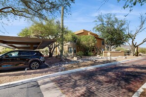 A modern house with a car parked in front, surrounded by trees and a clear sky. - Comfortable, Single-Level Condo with Free WiFi, Washer/Dryer, & Shared Pool (Tucson)