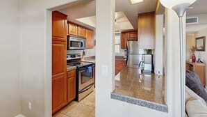A modern kitchen with wooden cabinets, stainless steel appliances, and a granite countertop. - Comfortable, Single-Level Condo with Free WiFi, Washer/Dryer, & Shared Pool (Tucson)
