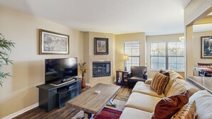 A living room with a flat-screen TV, a fireplace, a sofa, and a coffee table. - Comfortable, Single-Level Condo with Free WiFi, Washer/Dryer, & Shared Pool (Tucson)