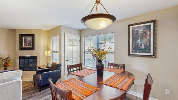 A dining area with a round table, chairs, and a chandelier. There is a fireplace, a sofa, and a window with blinds. - Comfortable, Single-Level Condo with Free WiFi, Washer/Dryer, & Shared Pool (Tucson)