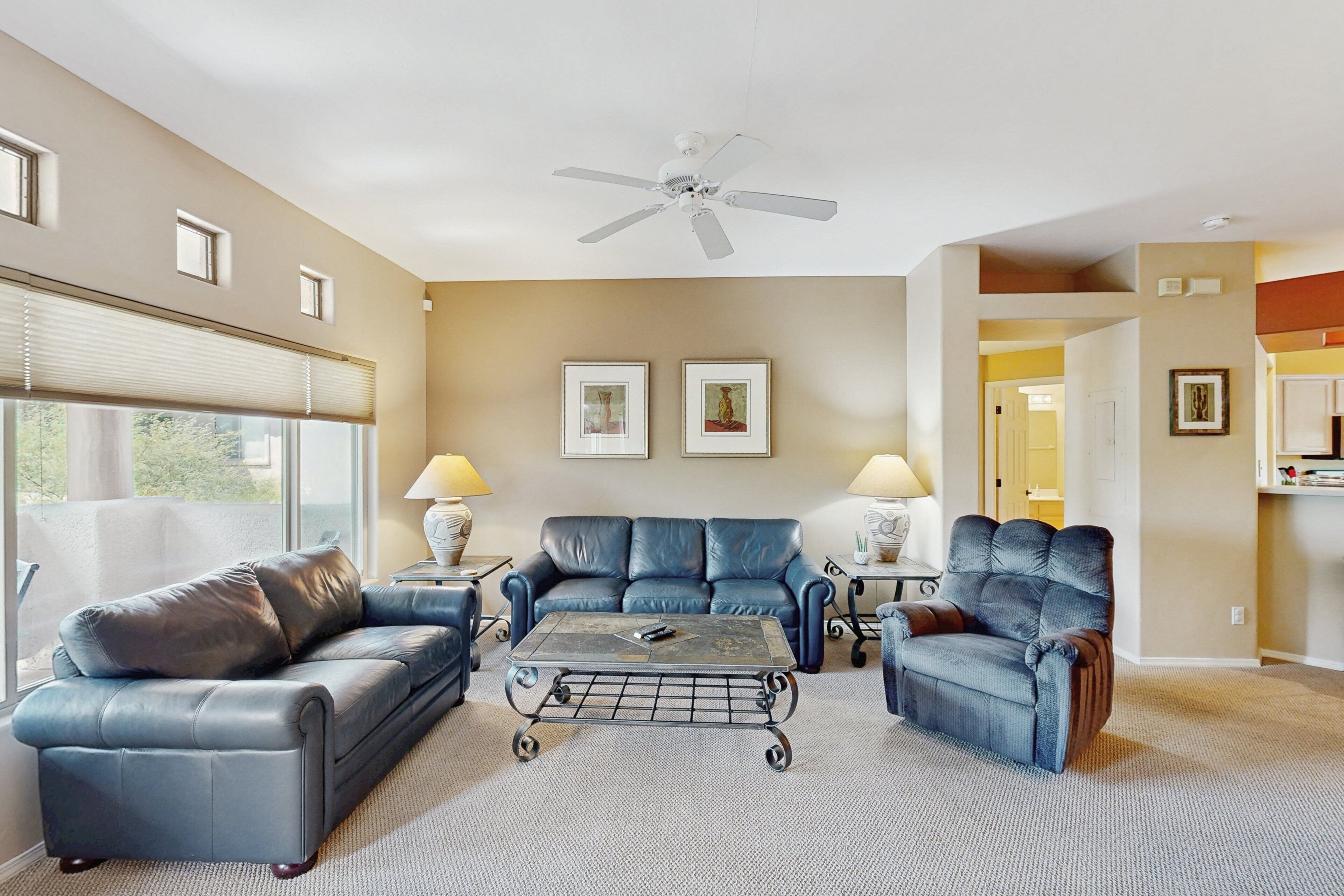 A living room with a ceiling fan, two sofas, a coffee table, and framed artwork on the wall.