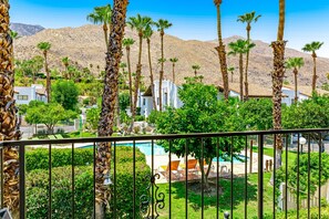 A view of a residential area with palm trees, a swimming pool, and houses with white exteriors. - Modern condo with mountain view, private balcony, pools (Palm Springs)