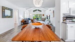 Een ruime eetruimte met een grote houten tafel en een opvallende geometrische hanglamp.