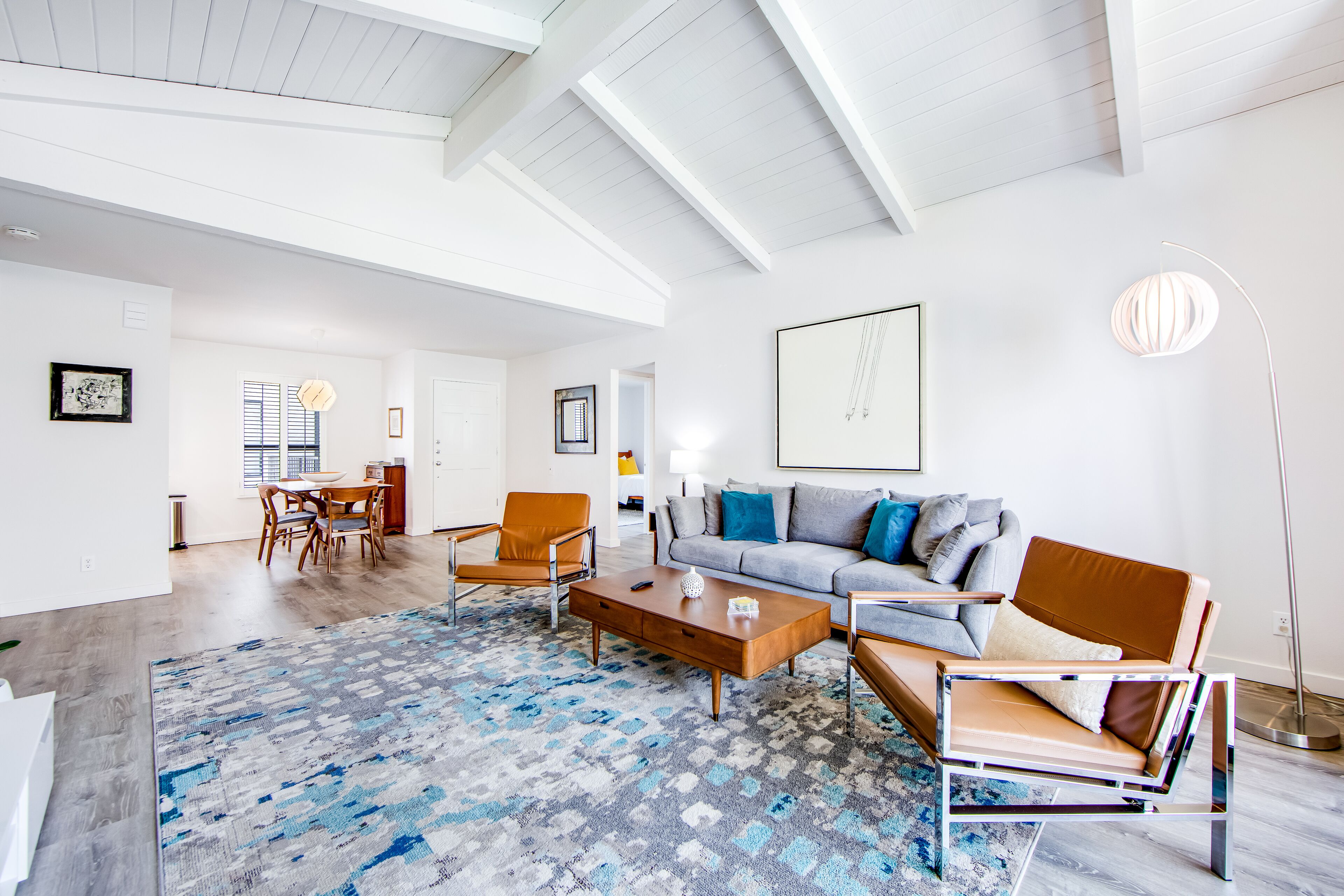 Uma sala de estar ampla com um sofá moderno, uma mesa de centro de madeira e um tapete estampado.