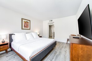 Een hotelkamer met een bed, nachtkastjes, een televisie en een bureau.