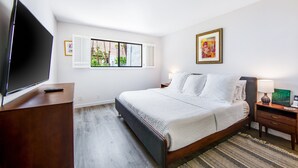 Een hotelkamer met een bed, een televisie, een bureau en kunst aan de muren.