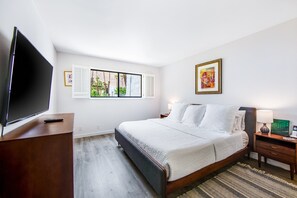 A hotel room with a bed, a TV, a desk, and artwork on the walls. - Modern condo with mountain view, private balcony, pools (Palm Springs)