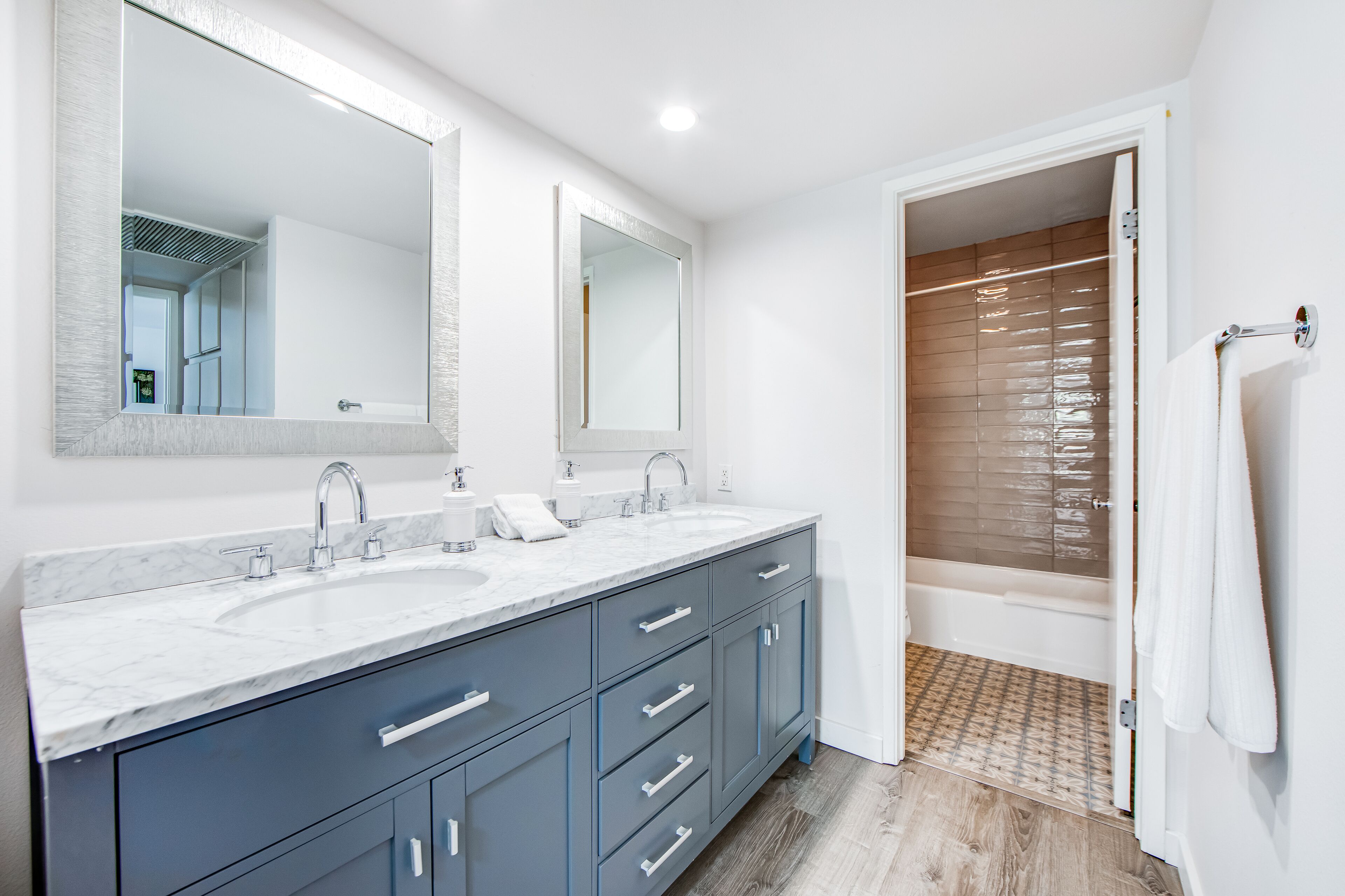 Une salle de bain moderne avec deux lavabos, un grand miroir et un espace douche.