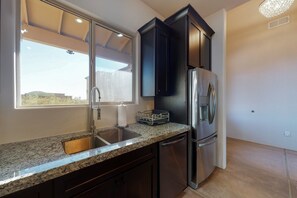 A modern kitchen with granite countertops, stainless steel appliances, and a window with a view. - Updated home with mountain views, a private patio, grill, EV charger, W/D, & AC (Tucson)