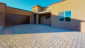 Ein modernes Gebäude mit Garage, überdachter Einfahrt und befestigter Auffahrt.