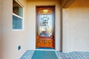 A wooden door with a decorative glass panel and a metal handle. - Updated home with mountain views, a private patio, grill, EV charger, W/D, & AC (Tucson)