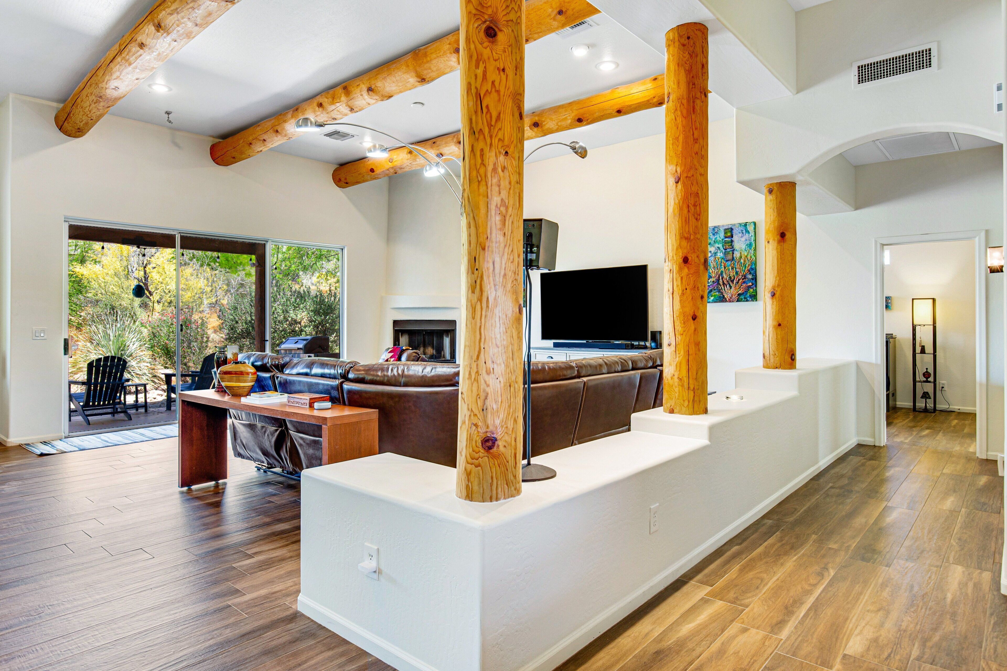 A spacious living area with a large wooden beam structure, a leather sofa, and a flat-screen TV.