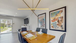 Zona pranzo con tavolo in legno, sedie nere e lampadario moderno.