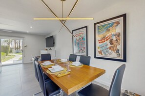 A dining area with a wooden table, black chairs, and a modern chandelier. - Relax, dine, and explore with ease soak up the sunshine. Home is Dog Friendly. (Palm Springs)