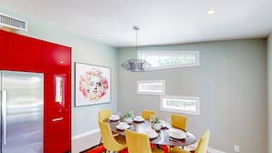 A modern dining area with a round table, yellow chairs, and a red refrigerator. - Mid-century modern retreat with pool/spa & firepit - golf & mtn views (Palm Springs)