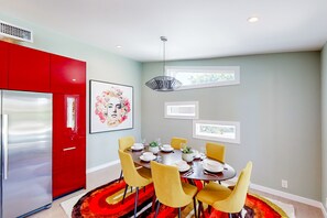A modern dining area with a round table, yellow chairs, and a red refrigerator. - Mid-century modern retreat with pool/spa & firepit - golf & mtn views (Palm Springs)