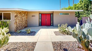 A modern building with a red door, numbered 2453, and a stone wall. - Mid-century modern retreat with pool/spa & firepit - golf & mtn views (Palm Springs)