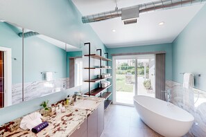A modern bathroom with a freestanding bathtub, marble countertops, and a large mirror. - Mid-century modern retreat with pool/spa & firepit - golf & mtn views (Palm Springs)