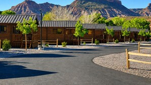 Une rangée de chalets en rondins, avec une allée pavée et une vue sur les montagnes en arrière-plan.