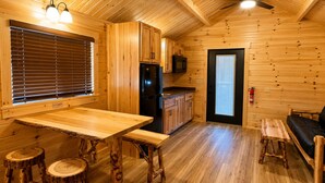 L’intérieur d’un chalet en bois comprend une cuisine, un coin repas et un espace salon.