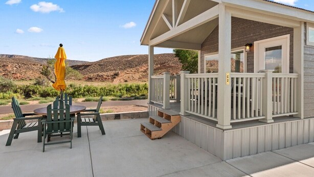 Un espace extérieur abrité, avec une table et des chaises, un parasol jaune et une vue sur un paysage désertique.