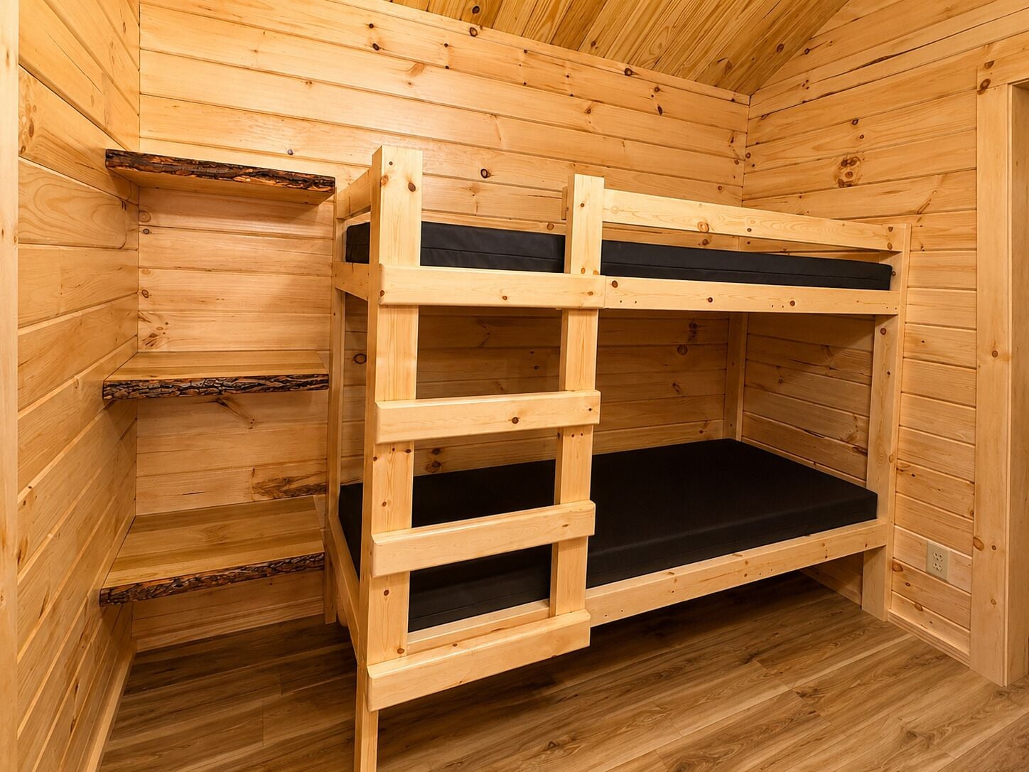 Una cama litera de madera con escalera, integrada en el interior de una cabaña rústica.