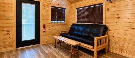 A wooden cabin interior with a sofa, a bench, and a door.
