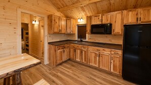 Un intérieur en bois comprenant un coin cuisine équipé de placards, d’un four à micro-ondes, d’un réfrigérateur et d’un évier.