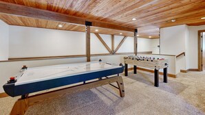 A room with a foosball table, pool table, and wooden ceiling beams. - Exquisite home with mountain views, fireplaces, game room & private Hot tub (Flagstaff)