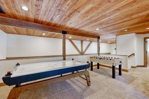 Une pièce dotée d’un baby-foot, d’une table de billard et de poutres en bois au plafond.