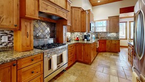 A kitchen with wooden cabinets, a stainless steel stove, and a tiled backsplash. - Exquisite home with mountain views, fireplaces, game room & private Hot tub (Flagstaff)