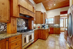 A kitchen with wooden cabinets, a stainless steel stove, and a tiled backsplash. - Exquisite home with mountain views, fireplaces, game room & private Hot tub (Flagstaff)