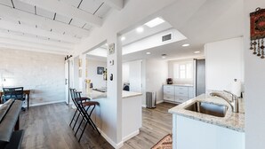 Een moderne keuken met een centraal eiland, een zithoek met een lange bank en een bar voorzien van krukken.