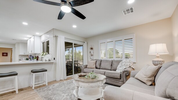 A spacious living area with a sofa, coffee table, and a dining area with a counter. - Ground-Floor Home w/Valley Views, Central A/C, Fast WiFi, & Private Washer/Dryer (Sun City)