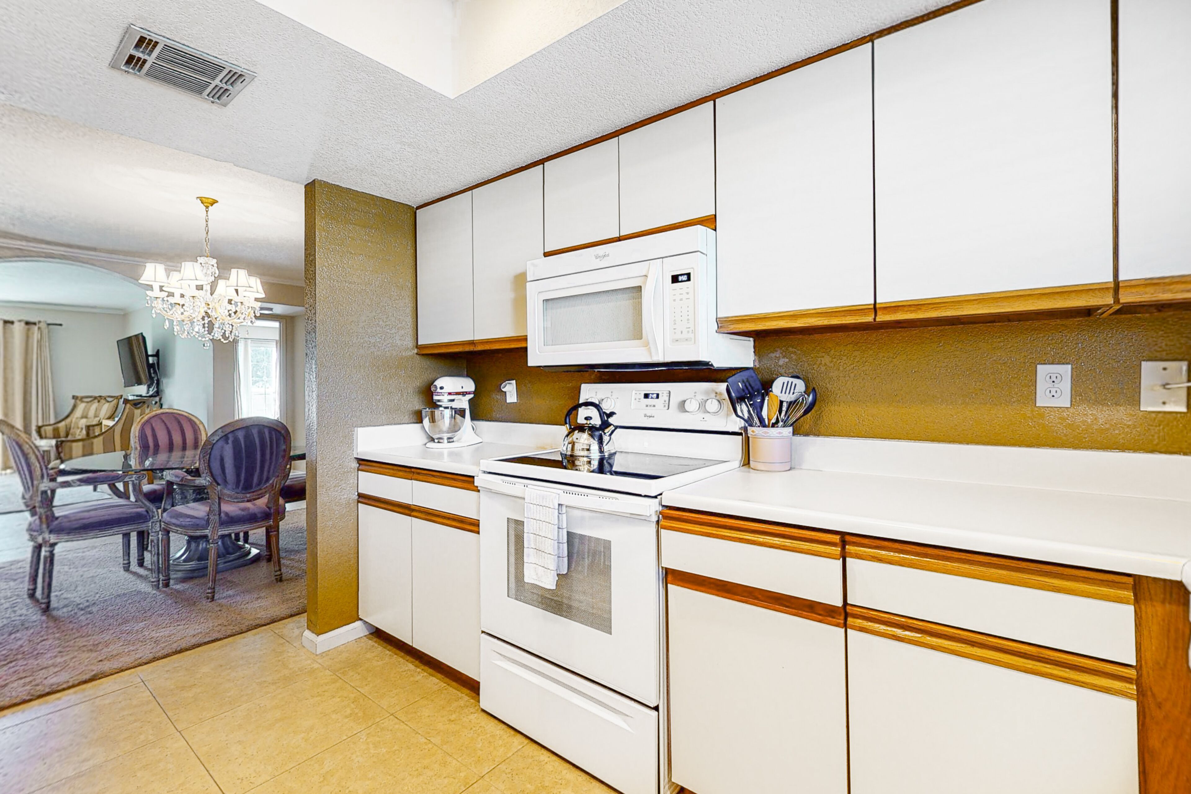 A kitchen with white cabinets, a microwave, a stove, and a dining area with chairs and a table.