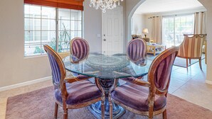 A dining area with a glass-top table surrounded by four chairs with cushioned seats. - Eclectic dog-friendly condo with gated entrance, pool & grill (Palm Springs)