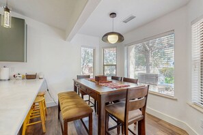 A modern kitchen with a large island, wooden chairs, and a hanging light fixture. - Dog-friendly home with garden patio, fireplace, & views of red rock cliffs (Sedona)