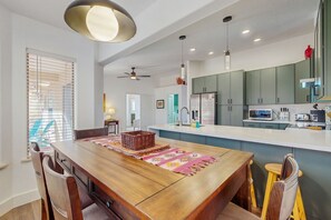 A modern kitchen with a central island, built-in appliances, and a dining area with wooden chairs. - Dog-friendly home with garden patio, fireplace, & views of red rock cliffs (Sedona)