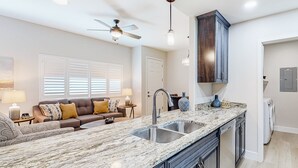 A modern kitchen with a large island, double sink, and dark cabinetry. - Beautiful dog-friendly condo with pool, central AC, & washer/dryer (Tucson)